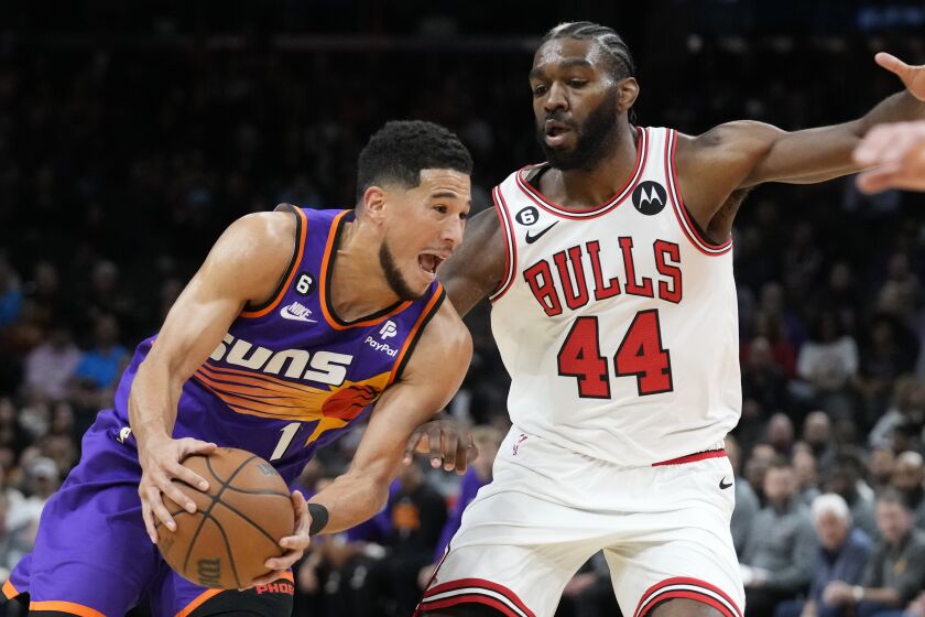 Phoenix Suns guard Devin Booker, left, drives past Chicago Bulls forward Patrick Williams (44) during the first half of an NBA basketball game in Phoenix, Wednesday, Nov. 30, 2022. (AP Photo/Ross D. Franklin)
