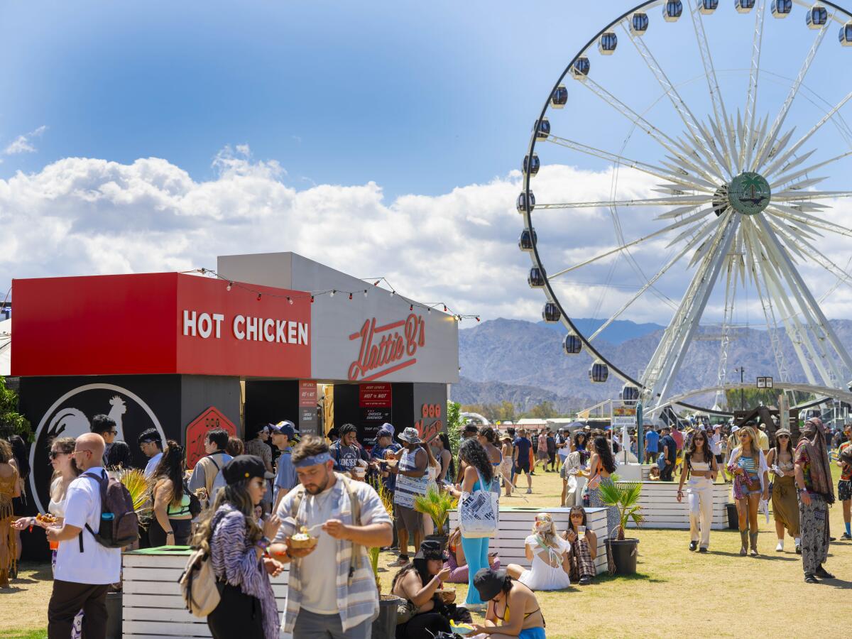 A crowd walks around the Coachella Valley Music and Arts Festival, with a Ferris wheel in the background