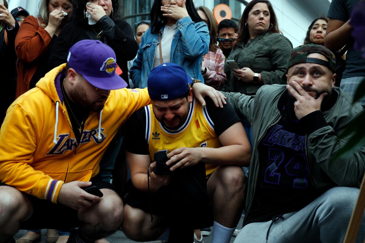 Fans Alex Fultz, Eddy Rivas and Rene Alfaro, left to right, stand near a memorial for Kobe Bryant who died in a helicopter crash on January 29, 2020, at Staples Center in Los Angeles, California.