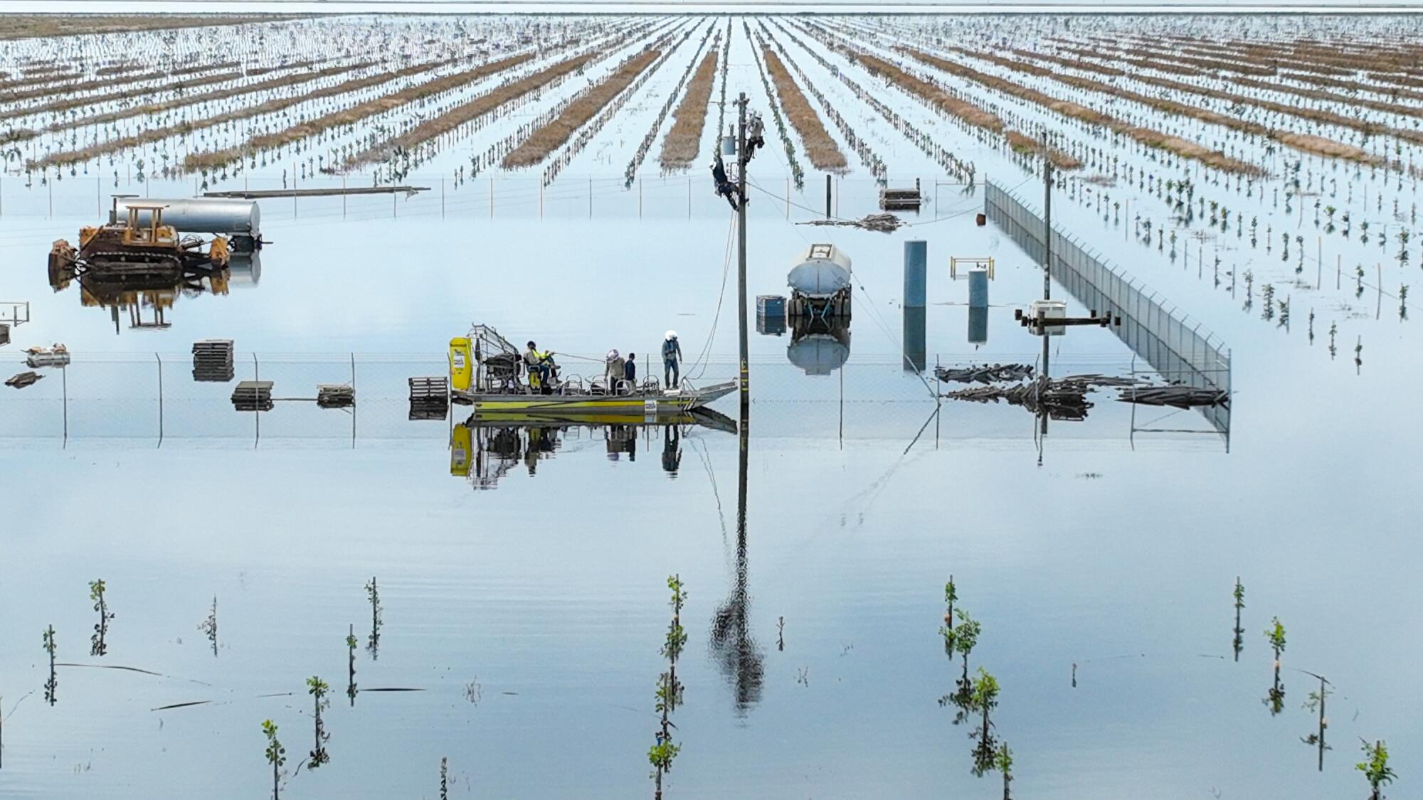 PG&E crews travel by airboat to decommission power lines in a flooded orchard. 
