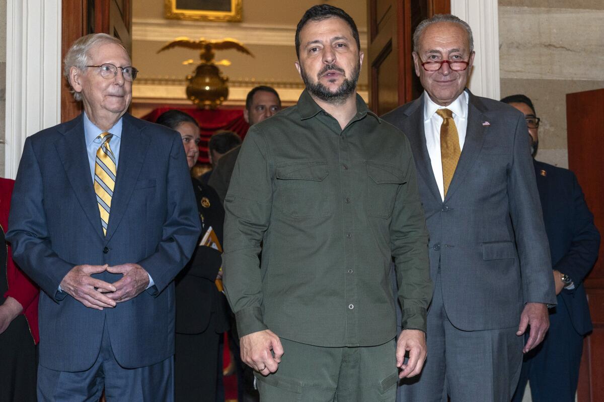 Volodymyr Zelensky stands between Mitch McConnell and Charles Schumer.