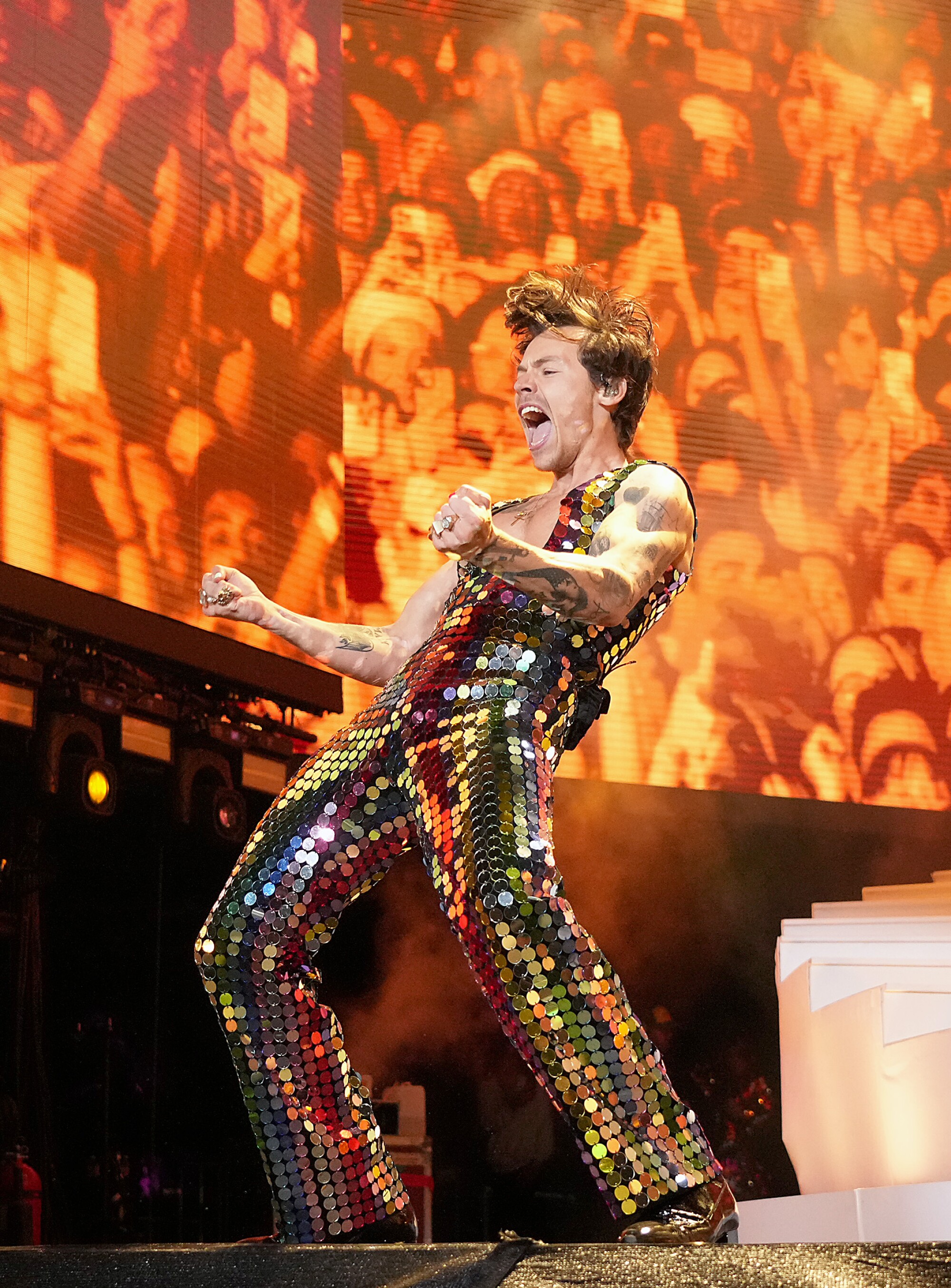 A male singer in a glittering bodysuit performs onstage