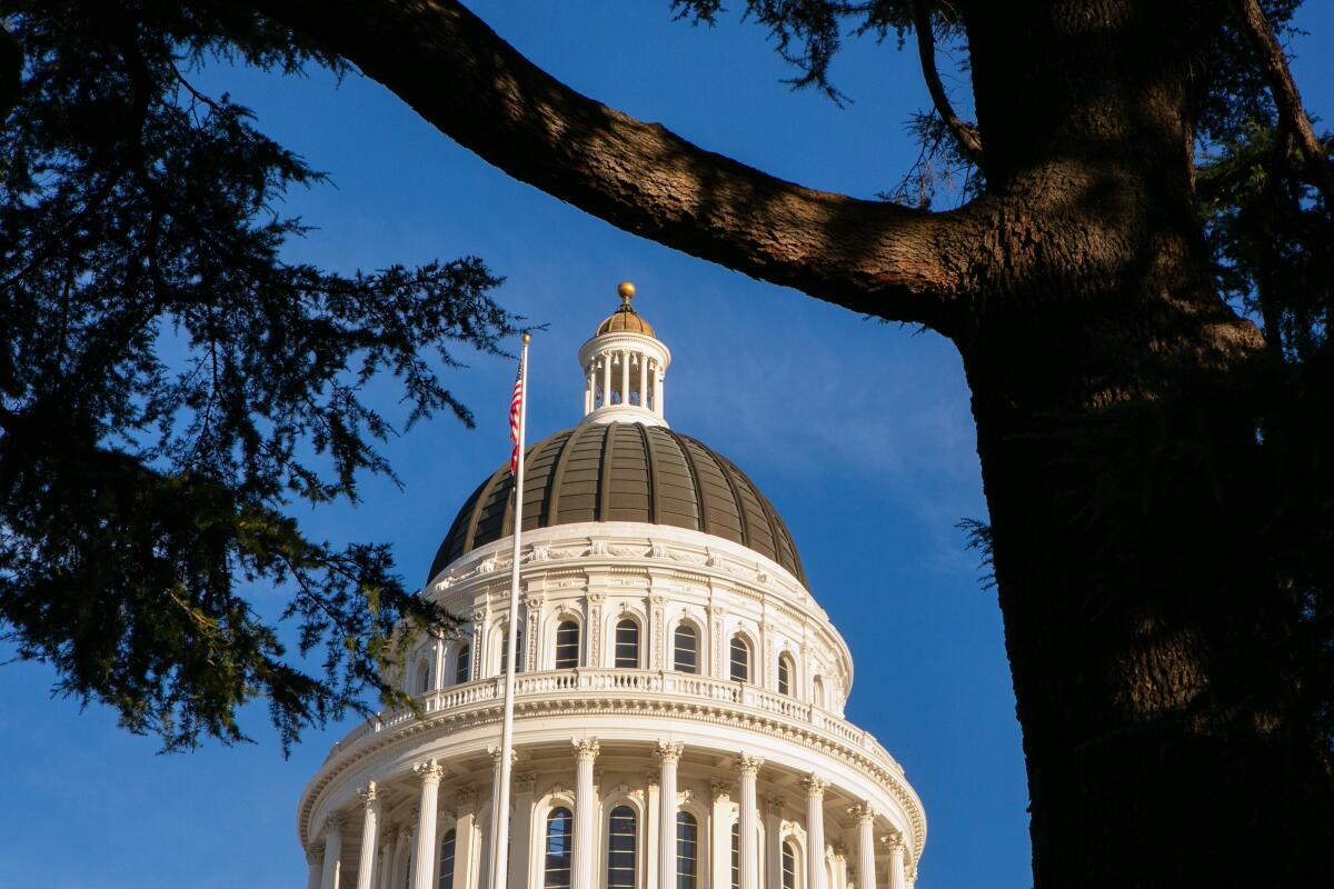 A U.S. flag flies in front of the white dome of the California Capitol