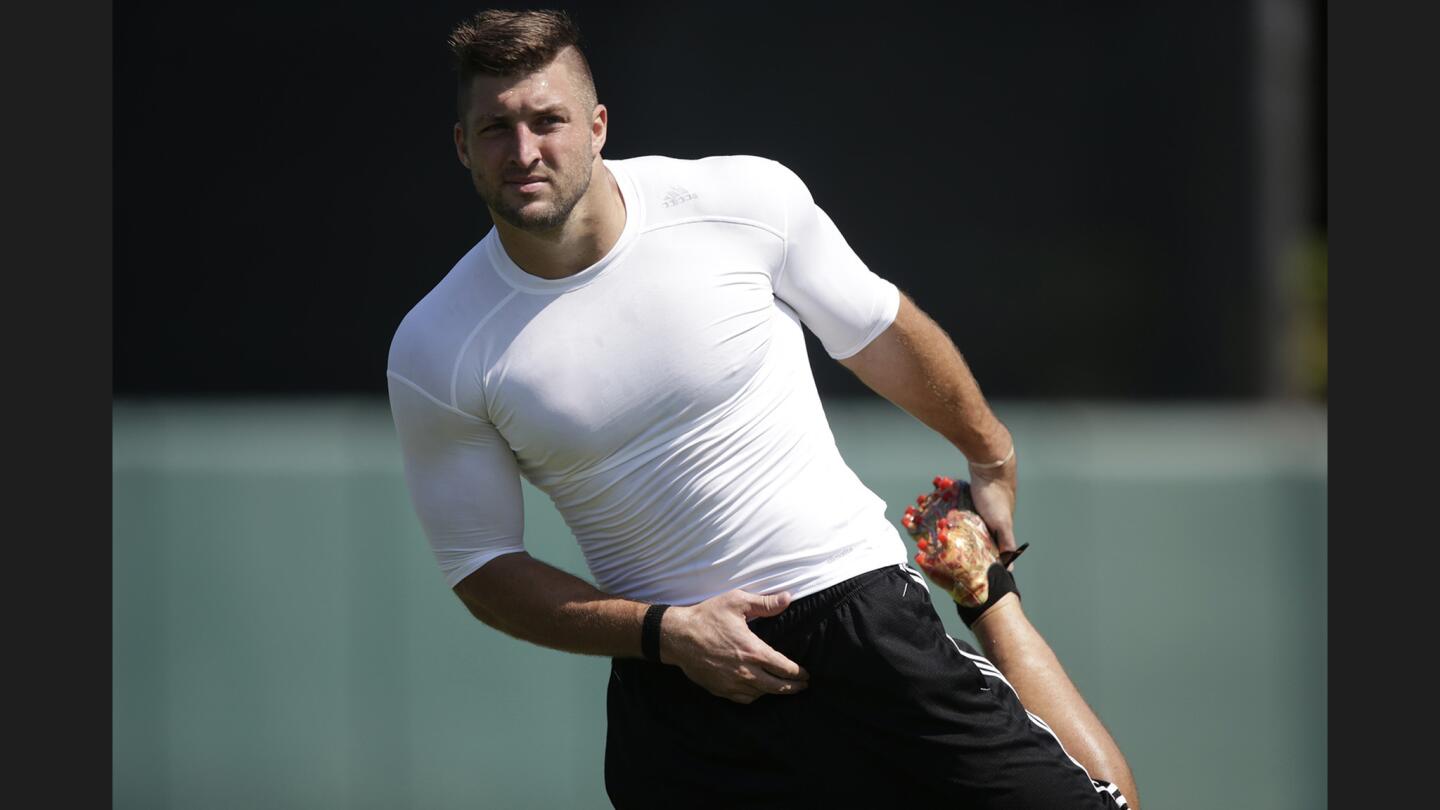 Former NFL quarterback Tim Tebow stretches as he prepares to run a 60-yard dash during a private baseball tryout at USC.