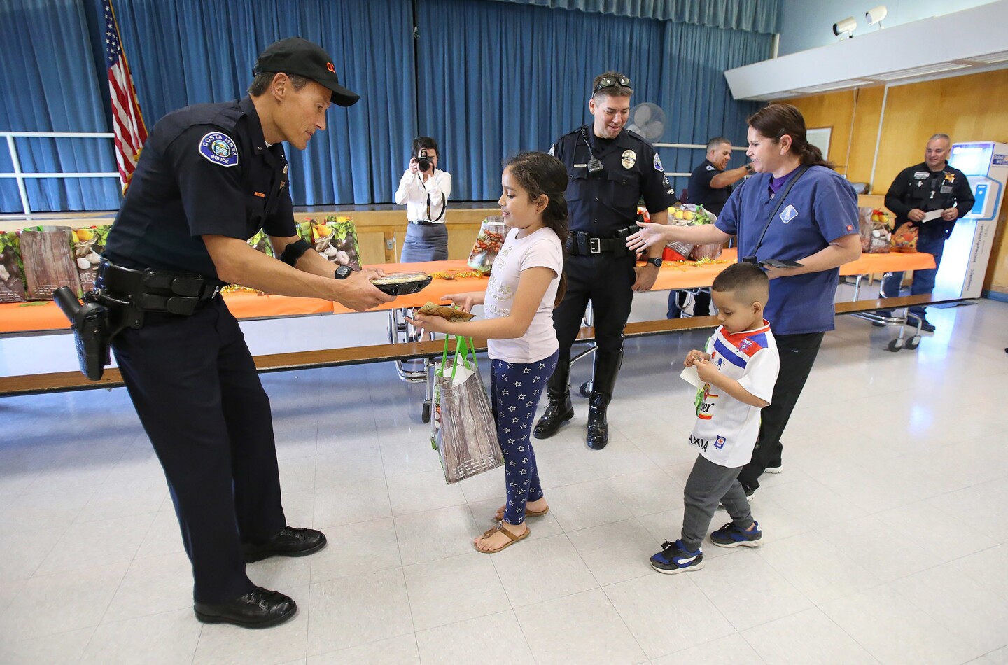 Costa Mesa police Lt. Greg Scott hands Destiny Jimenez a pumpkin pie Wednesday to go with a turkey dinner gift bag after she completed the anti-gang Thanksgiving challenge at Wilson Elementary School.
