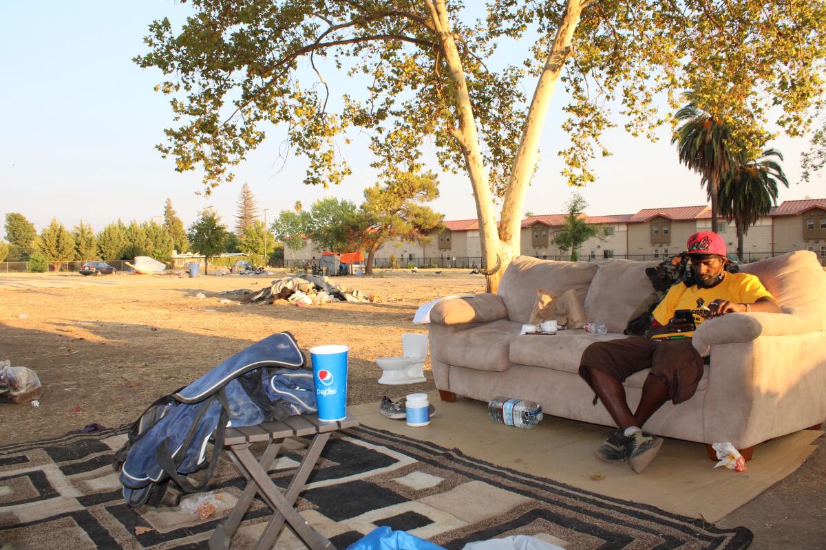 Donta Williams sits on a couch at an encampment in Sacramento. 