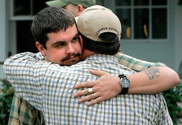 Josh Myers, left, a deputy with the Geneva County Sheriff's Department whose wife and daughter were killed in a Tuesday shooting in Samson, Ala., is consoled by a friend. The gunman killed 10 people across two Alabama counties.