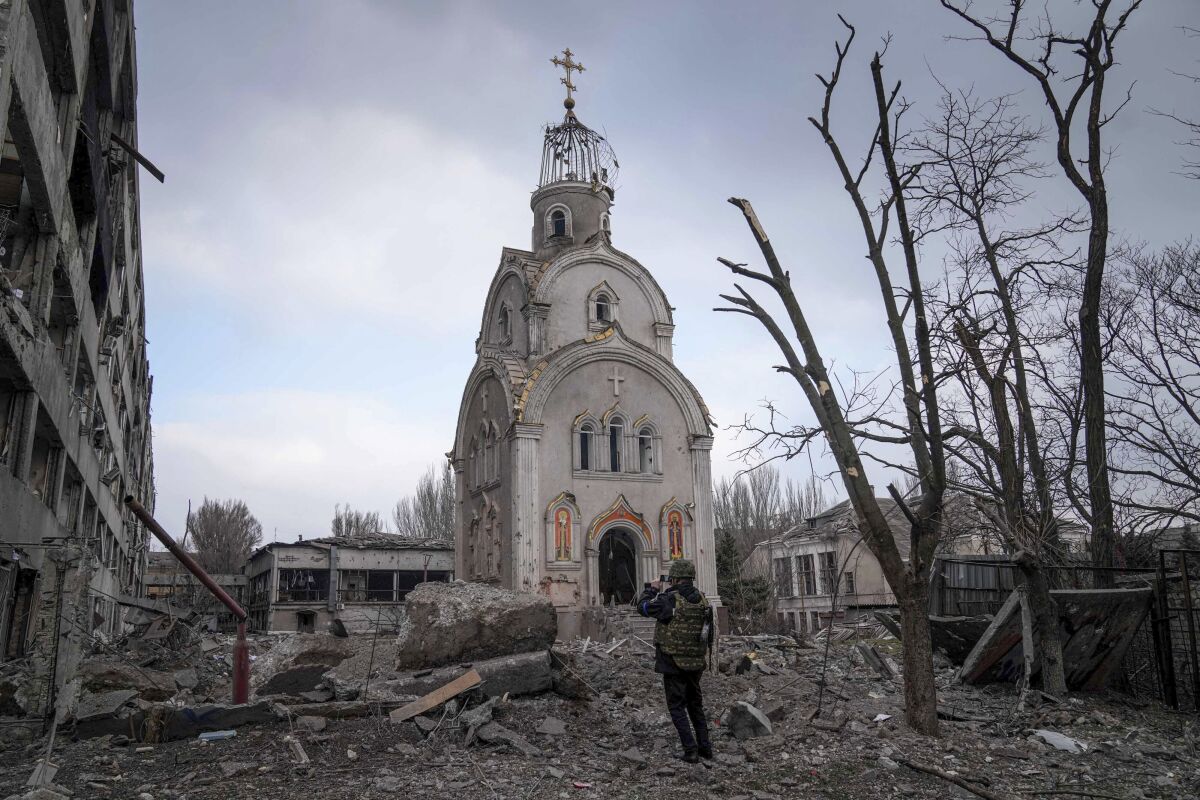 A Ukrainian serviceman takes a photograph of a damaged church 