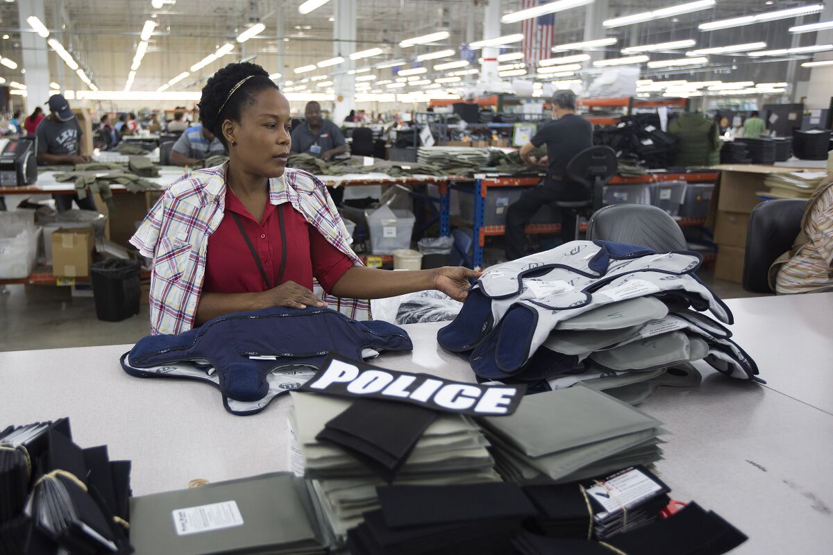 FILE - Laurette Eugene assembles a body armor vest at the Point Blank Body Armor factory in Pompano Beach, Fla., Sept. 19, 2014. When a shooter attacked a supermarket in Buffalo, New York,May 14, 2022, its security guard tried to stop him. At least one of the guard's shots hit the gunman, but it didn’t stop the deadly rampage because the gunman was wearing body armor. (AP Photo/J Pat Carter, File)