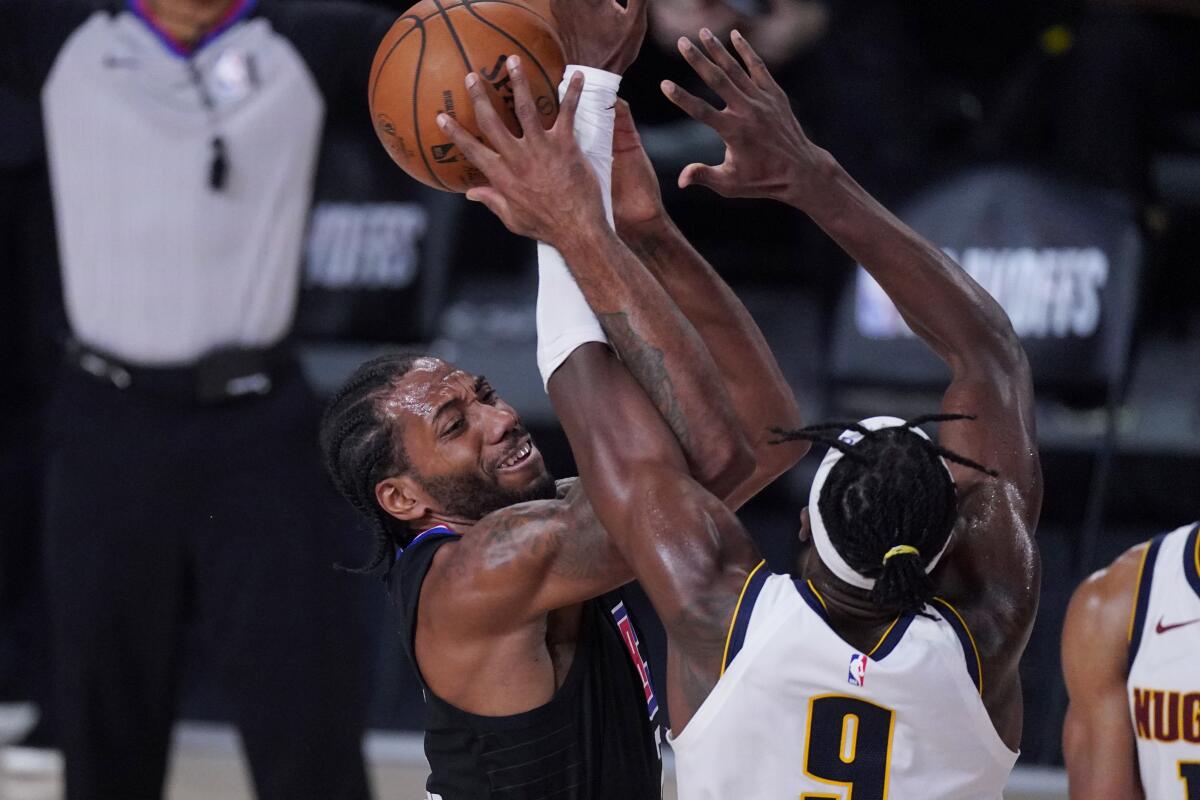 Clippers forward Kawhi Leonard is defended by Denver Nuggets forward Jerami Grant.