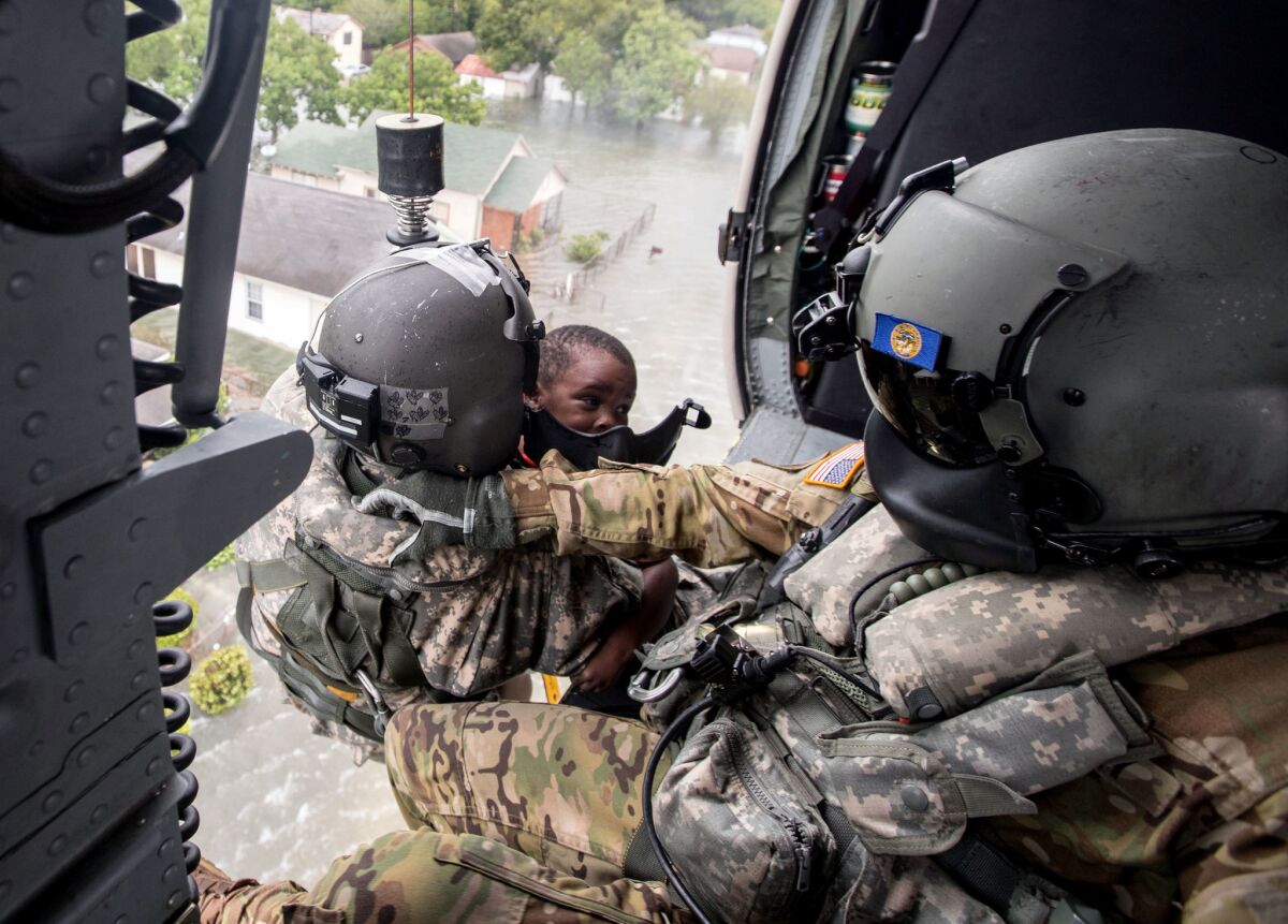 Staff Sgt. Lawrence Lind, left, hoists a child into a Black Hawk helicopter while Sgt. Ray Smith helps the boy who was rescued in Port Arthur, Texas.