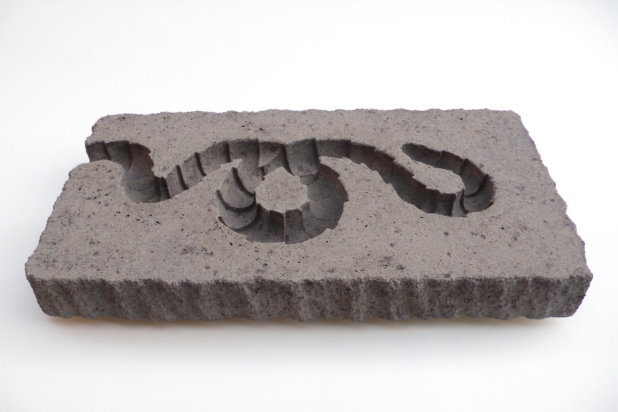 A gray rectangle of a stone-like material, with a snake carved deeply into its surface
