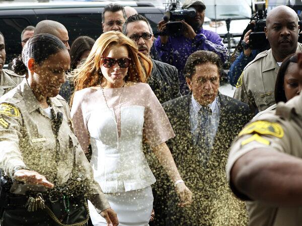 Actress Lindsay Lohan is showered with gold glitter as she walks with her attorney, Mark Heller, into Los Angeles County Superior Court. She has been charged with three misdemeanor counts stemming from a car crash in 2012 on Pacific Coast Highway.