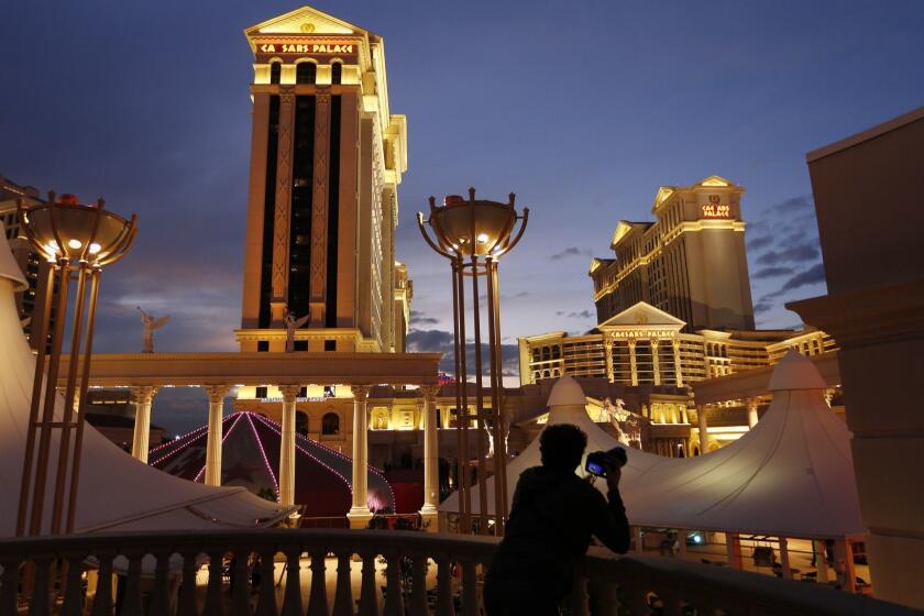 FILE - In this Jan. 12, 2015, file photo, a man takes pictures of Caesars Palace hotel and casino, in Las Vegas. Eldorado Resorts will buy Caesars in a cash-and-stock deal valued at $17.3 billion, creating a casino giant. The acquisition Monday, June 24, 2019, puts about 60 casinos and resorts in 16 states under a single name, one of the biggest gambling and entertainment ventures in the United States. (AP Photo/John Locher, File)