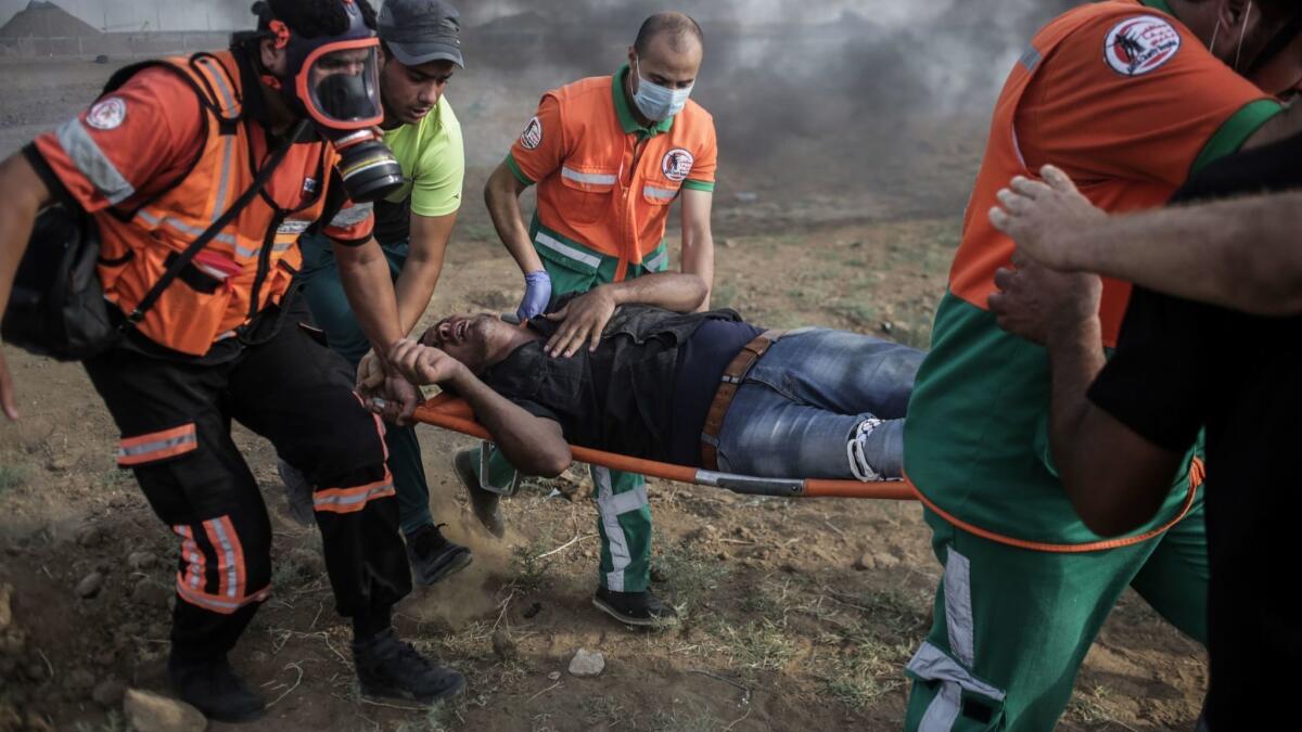 Palestinians carry a wounded protester during clashes with Israeli troops along the Israel-Gaza Strip border Friday.