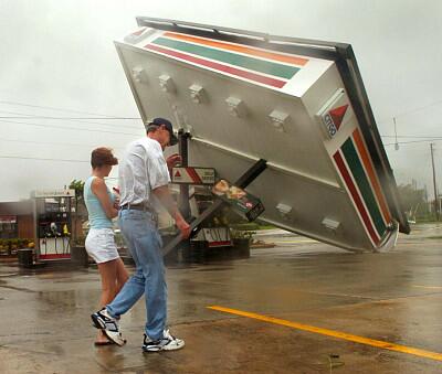 Evacuees Jim Christian and Shantel Morgan walk by a toppled gas station roof at a 7-11 store on Lee Road in north Orlando, shortly after the effects of the storm blew through Orlando.