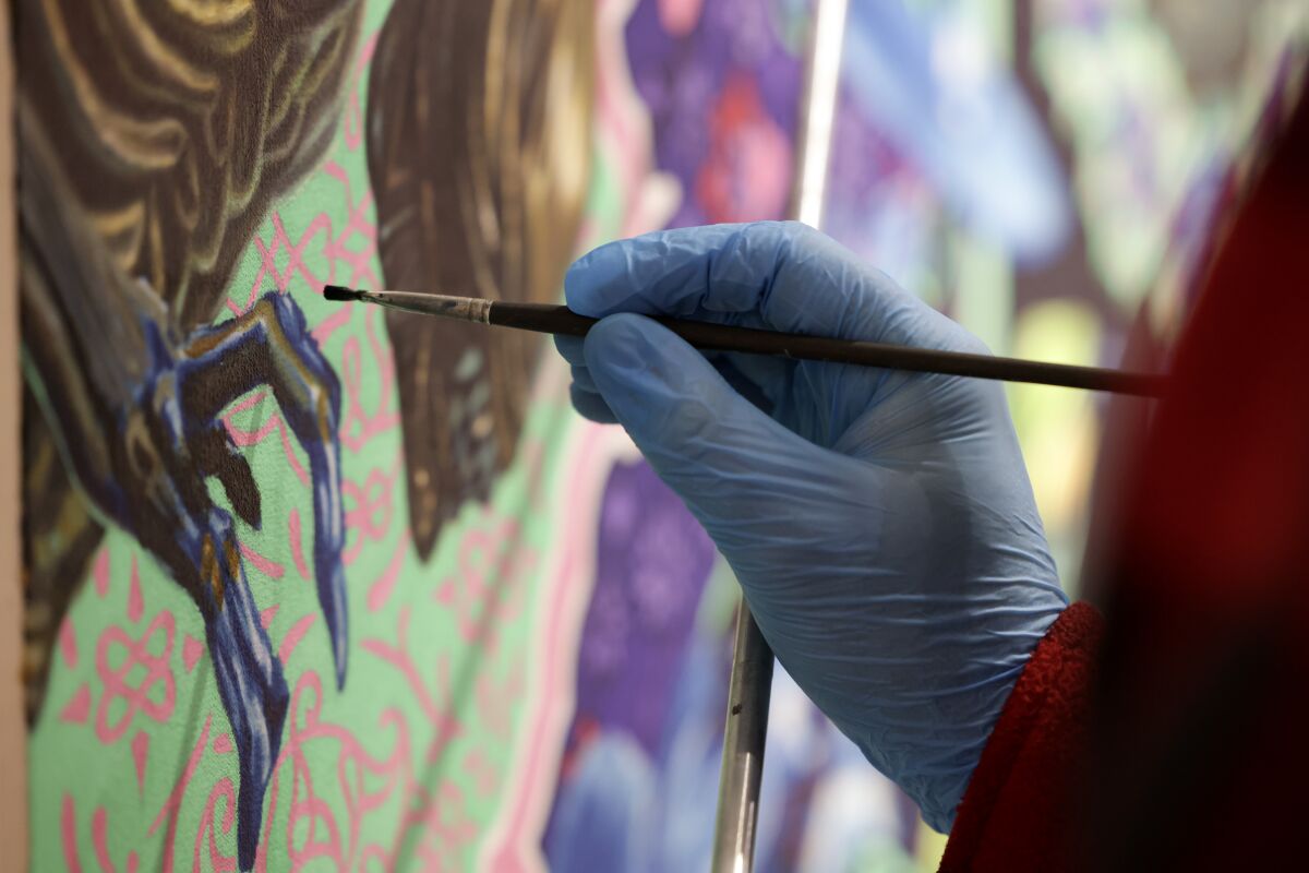Artist Robert Xavier Burden works on his painting titled "The Alien Painting" at the Oceanside Museum of Art.