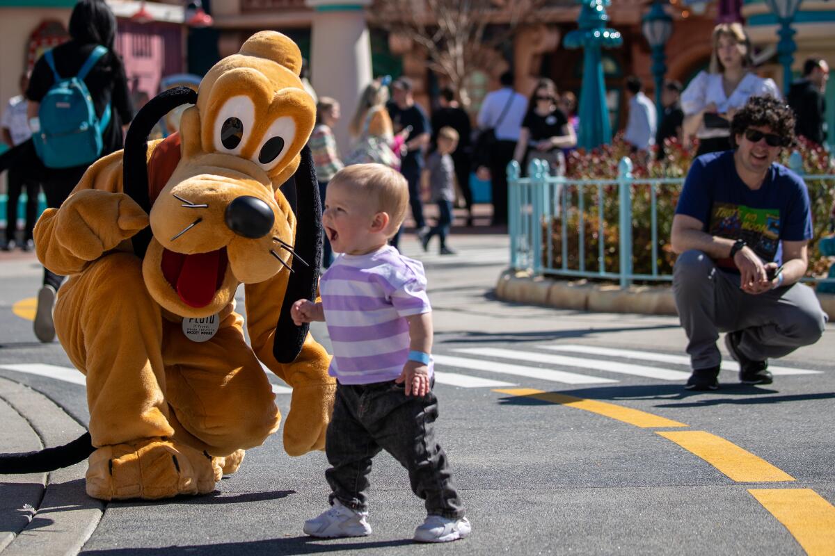 Disney character Pluto entertains a little visitor in Toontown at Disneyland.