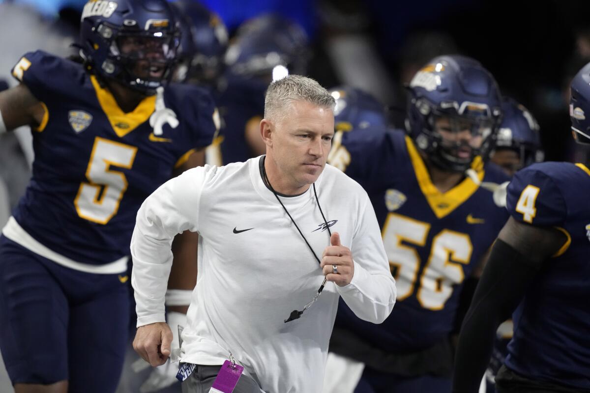 Toledo coach Jason Candle runs onto the field with his players before playing Miami (Ohio).