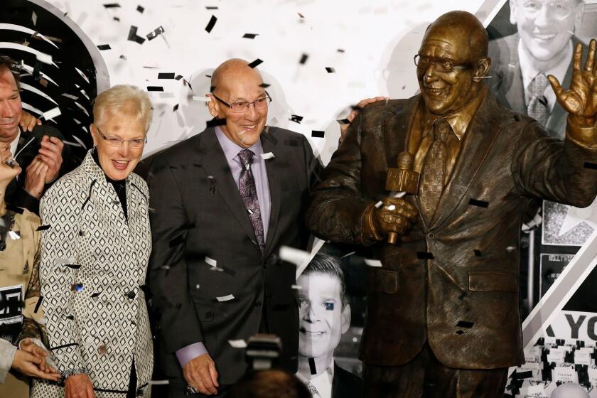 A statue honoring former Los Angeles Kings broadcaster Bob Miller, center, is unveiled in Star Plaza outside Staples Center, as Miller stands with his wife, Judy Miller, third from left, and other family members before the Kings' NHL hockey game against the Anaheim Ducks in Los Angeles, Saturday, Jan. 13, 2018. (AP Photo/Alex Gallardo)