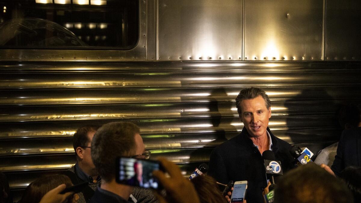 Gavin Newsom speaks with the media after he and his family attend an Inauguration event Sunday at Sacramento's California Railroad Museum.