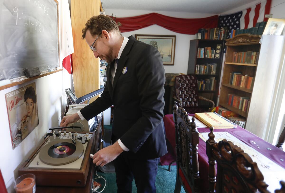 Dressed in a black suit, white shirt and narrow tie, common in the 1960s, Gideon Marcus plays a 45rpm record of the song, "Dancing in the Street" by Martha and the Vandellas in 1964, in what he calls the War Room, October 2, 2019, in Vista, California. He is the founder of Galactic Journey, an award-winning science blog by the same name that's written as if it takes place 55 years to the day in the past. He also has a low-power AM and FM radio stations, as well as a TV station that all broadcasts programming from the 1960s.