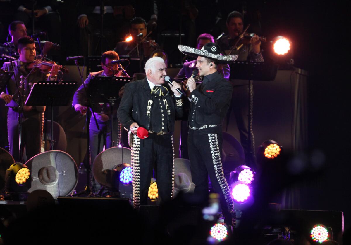 A man and a younger man singing into microphones on a stage