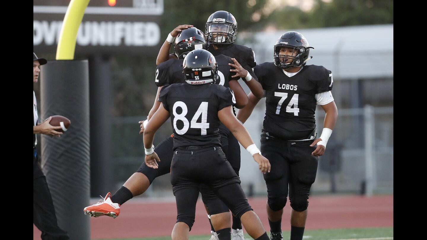 Los Amigos High's Brian Pacheco, top center, celebrates with teammates after scoring the Lobos' first touchdown against Saddleback during the first half in a nonleague game at Garden Grove High School on Thursday, Sept. 6.