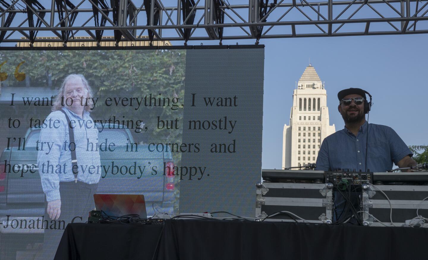 DJ Anthony Valadez of KCRW and images of Jonathan Gold appear onstage as visitors gather at Grand Park for a public memorial and celebration for the life of Los Angeles Times writer Jonathan Gold in Los Angeles on Aug. 26, 2018. Gold, who died July 21 of pancreatic cancer, was the paper's Pulitzer Prize-winning restaurant critic.