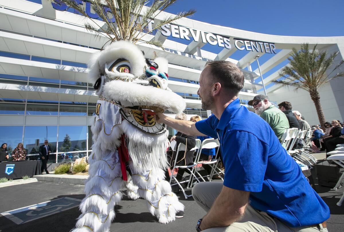 Michael Hohertz places a red envelope in the mouth of a Southern Wind Lion Dancer.