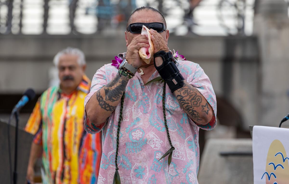 A man holds a shell to his mouth