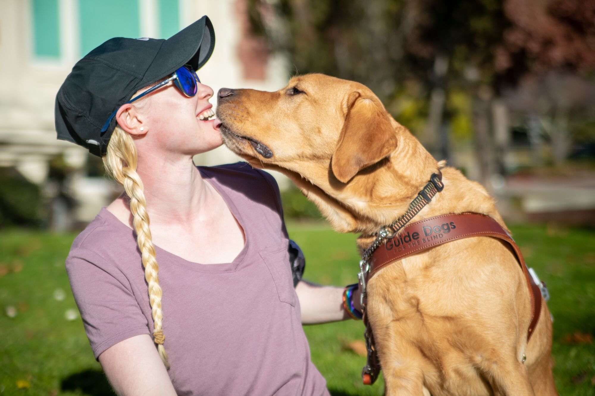 Paralympic runner Kym Crosby laughs as her guide dog Tron licks her face.