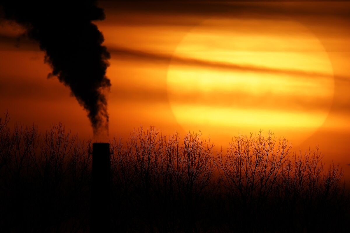 Emissions from a coal-fired power plant are silhouetted against the setting sun