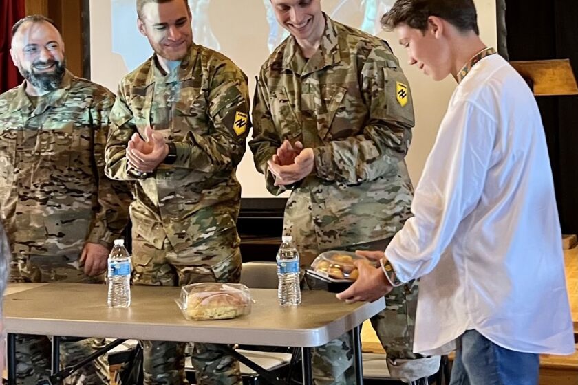 Ukrainian soldiers are greeted with a traditional gift of bread before sharing their Russian war experiences in Del Mar event