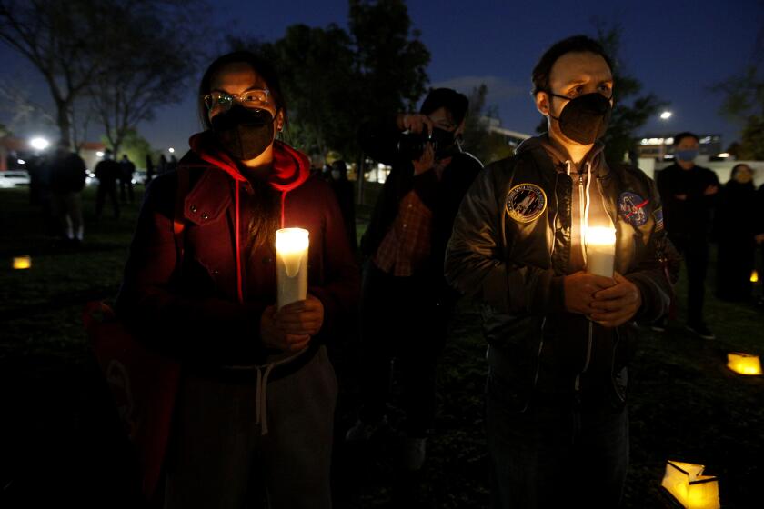 Anne Chua Lee, left, and Pablo Bert, both from Long Beach, came to a candlelight vigil to stop Asian hate, at Community Center Park, in Garden Grove on Tuesday, March 23, 2021.
