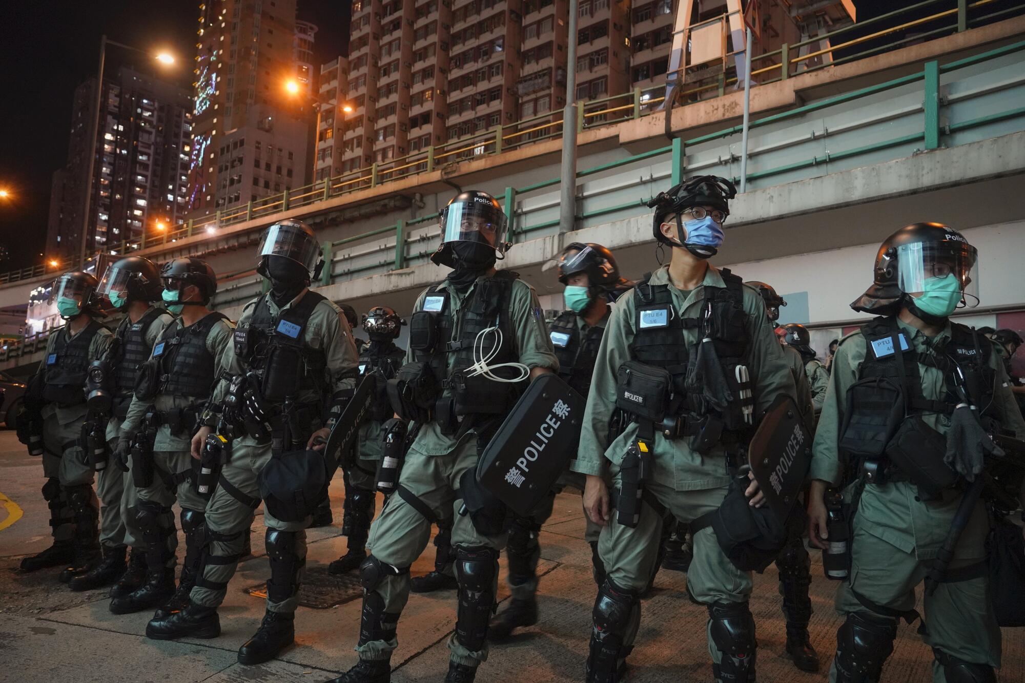 Riot police stand guard after pushing back protesters demonstrating against the new security law 