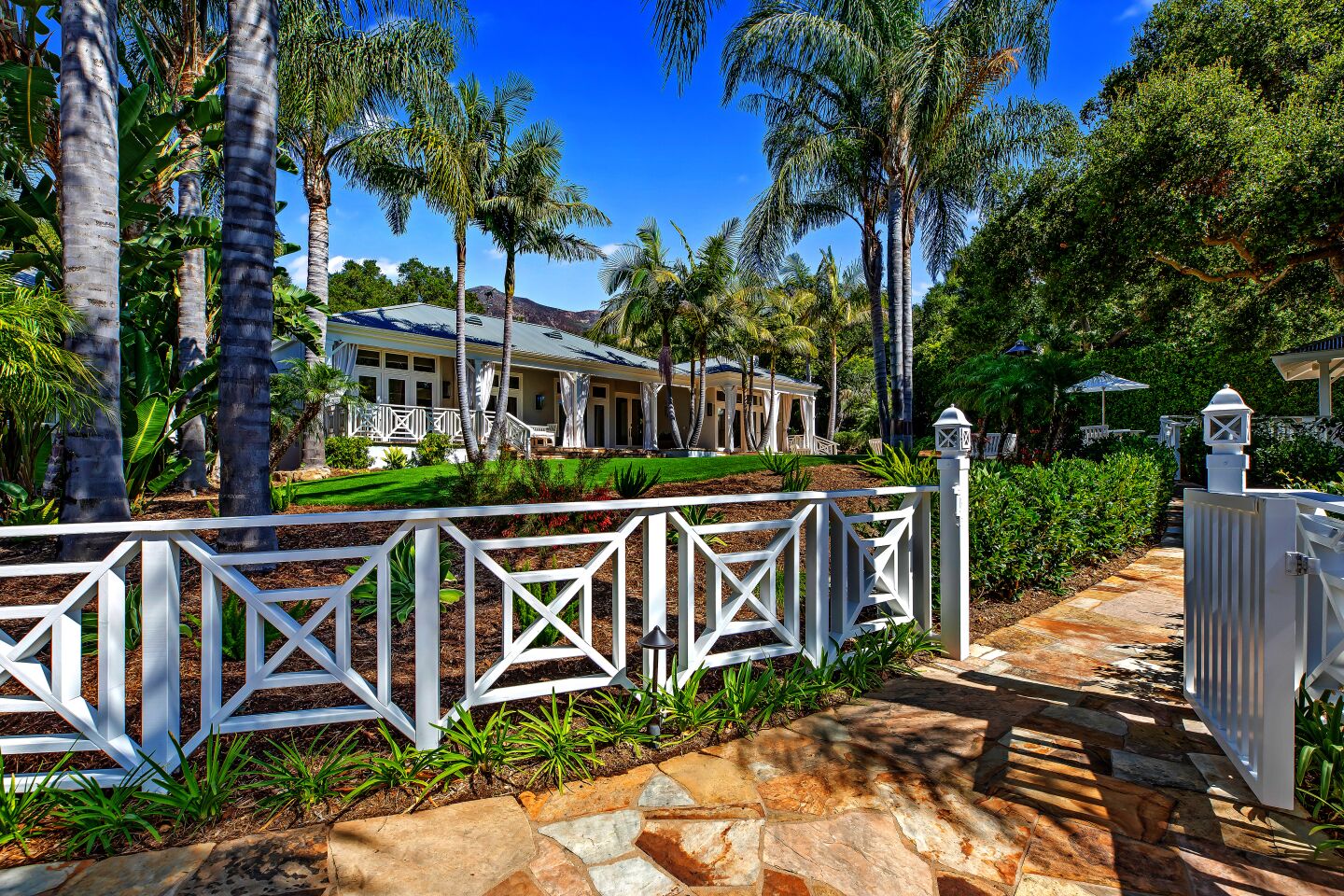 The estate, which features a Bermuda-style main house and guest house, sits on a one-acre lot dotted with palm trees and tropical plants native to Hawaii.