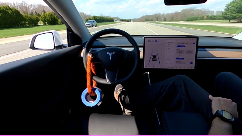 A weight hangs from the steering wheel of a Tesla to defeat the Autopilot driver monitoring system. 