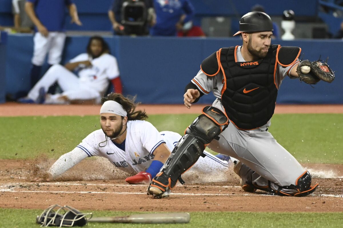 Toronto Blue Jays' Bo Bichette, left, slides safely into home ahead of a tag by Baltimore Orioles catcher Austin Wynns on a single by Blue Jays' Teoscar Hernandez during the fourth inning of a baseball game in Toronto on Wednesday, Sept. 1, 2021. (Jon Blacker/The Canadian Press via AP)