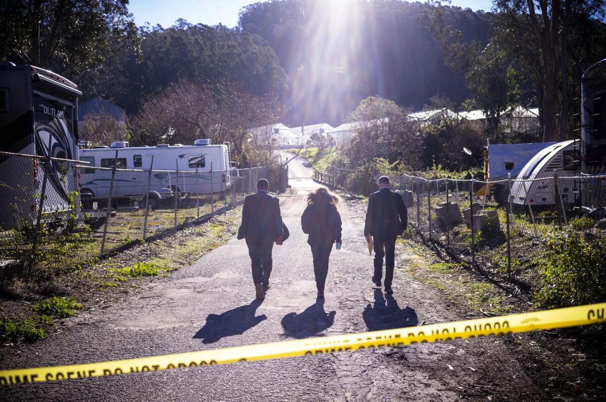 FBI officials walk behind crime-scene tape toward a farm.