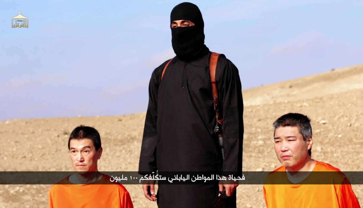 A video purportedly released by Islamic State on Jan. 20 shows Japanese hostages Kenji Goto, left, and Haruna Yukawa with a militant at an undisclosed location.