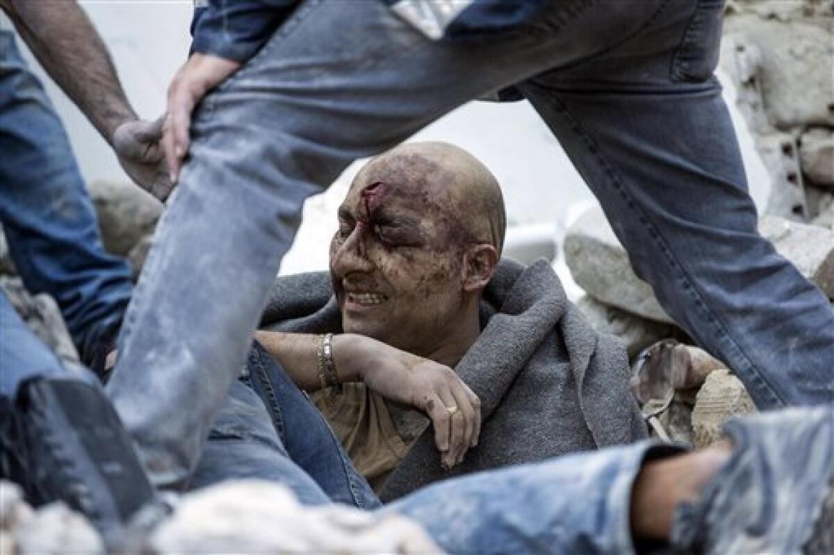 Un hombre recibe ayuda para salir de debajo de los escombros tras el sismo que sacudió la localidad de Amatrice, en el centro de Italia, el 24 de agosto de 2016.