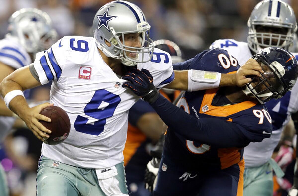 Cowboys quarterback Tony Romo tries to fend off a sack by Broncos defensive end Shaun Phillips late in the fourth quarter Sunday.