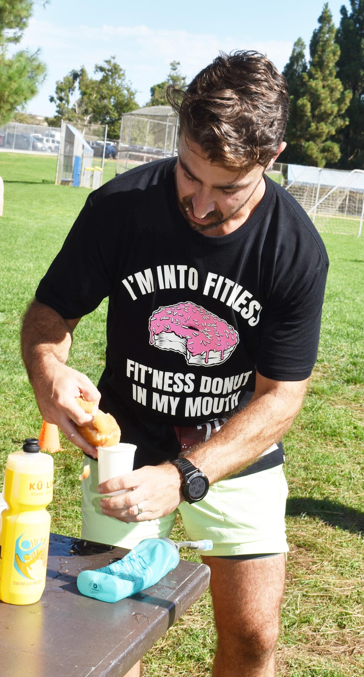 Ryan Marcoux dipping a doughnut into a cup of water to help him eat it faster during the Donut Mile race.