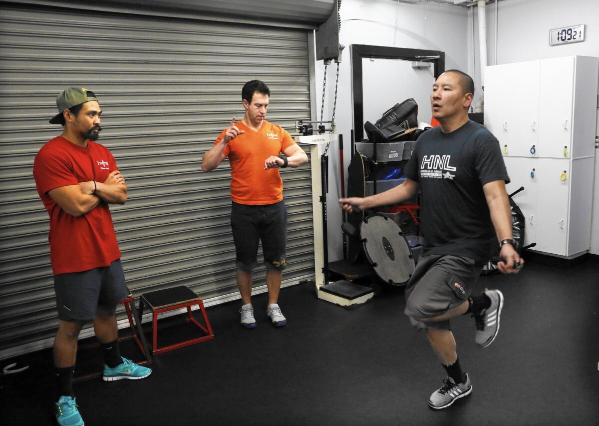 Trainer Steve Zim, center, and assistant Bryan Arceo work with Culver City Police Officer Tri Lai as he regains his strength after a devastating motorcycle accident in 2013.