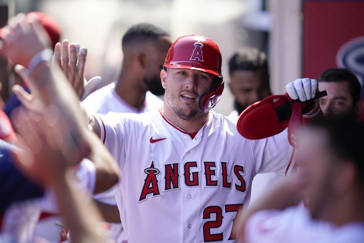 Angels' Mike Trout celebrates in the dugout after scoring off of a single hit by Taylor Ward.