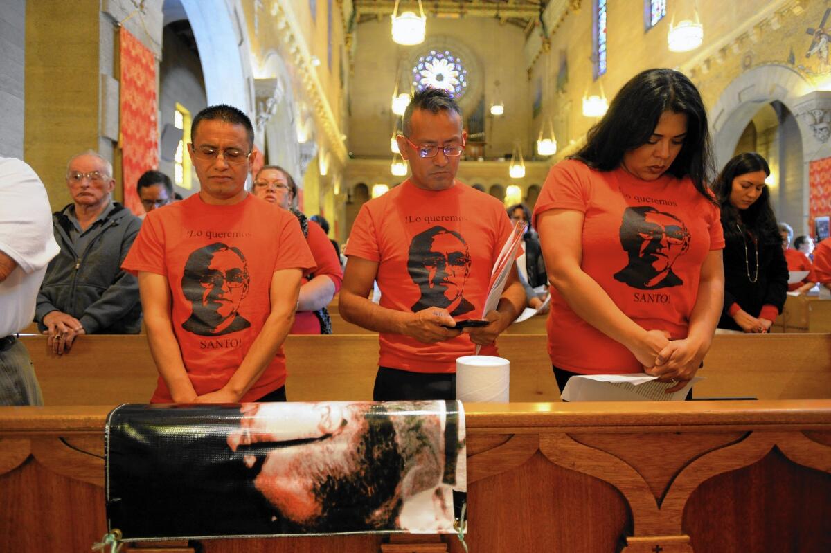 Carlos Paxtor, left, Jesus Roldan and Claudia Santos join a service and procession to remember Msgr. Oscar Romero at Precious Blood Catholic Church in L.A.