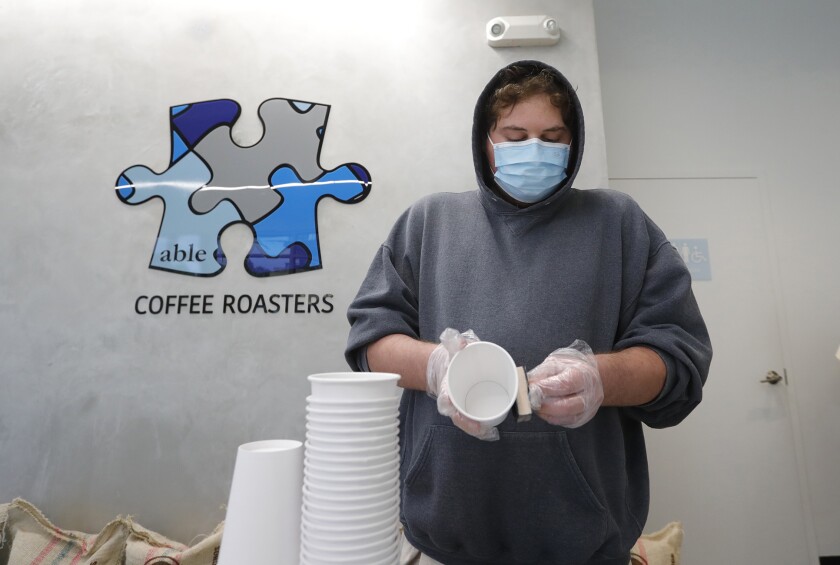 Un empleado de Able Coffee estampa el logotipo de la empresa en las tazas de café en la ubicación de Huntington Beach.