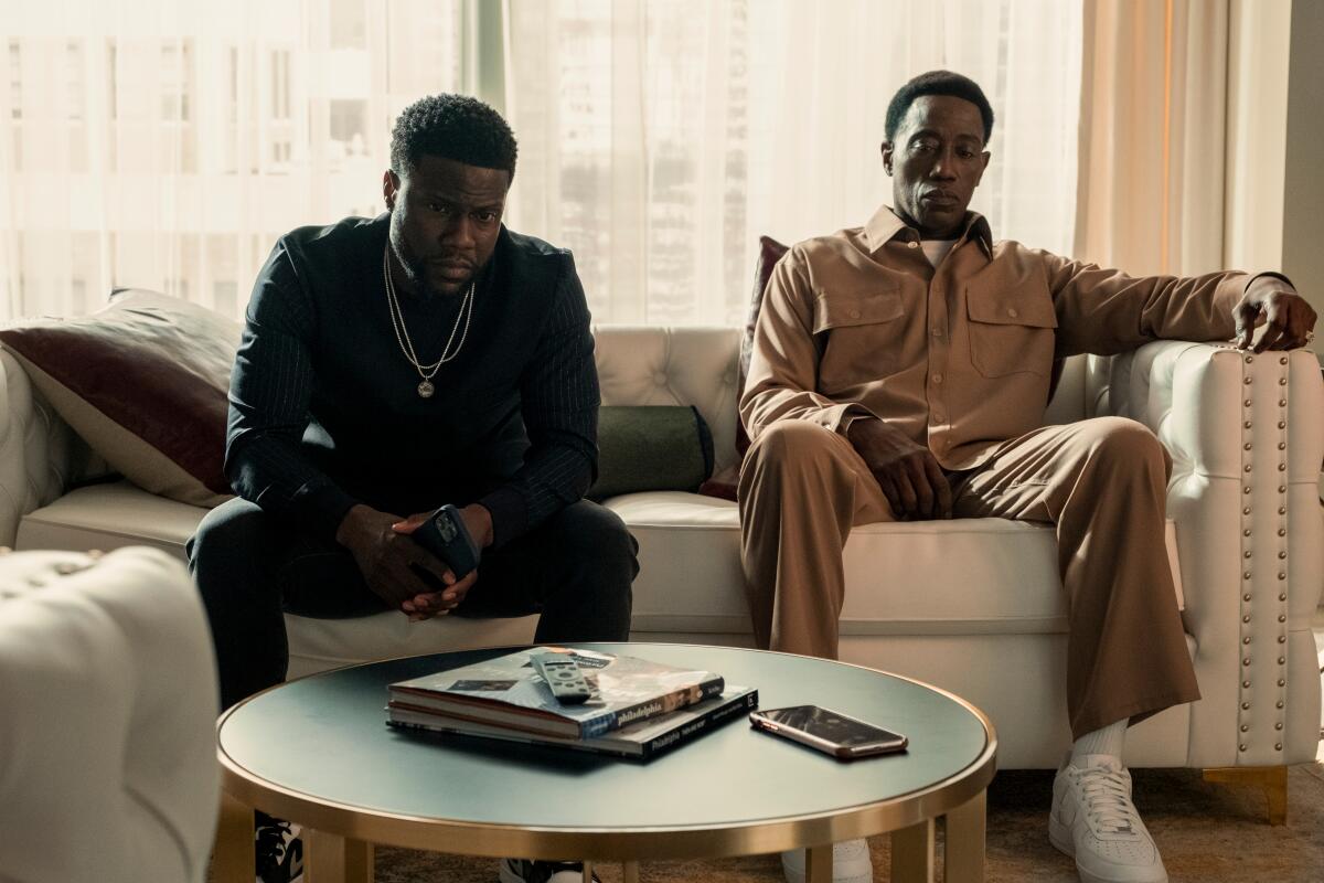 Kevin Hart and Wesley Snipes sit on a couch looking downcast