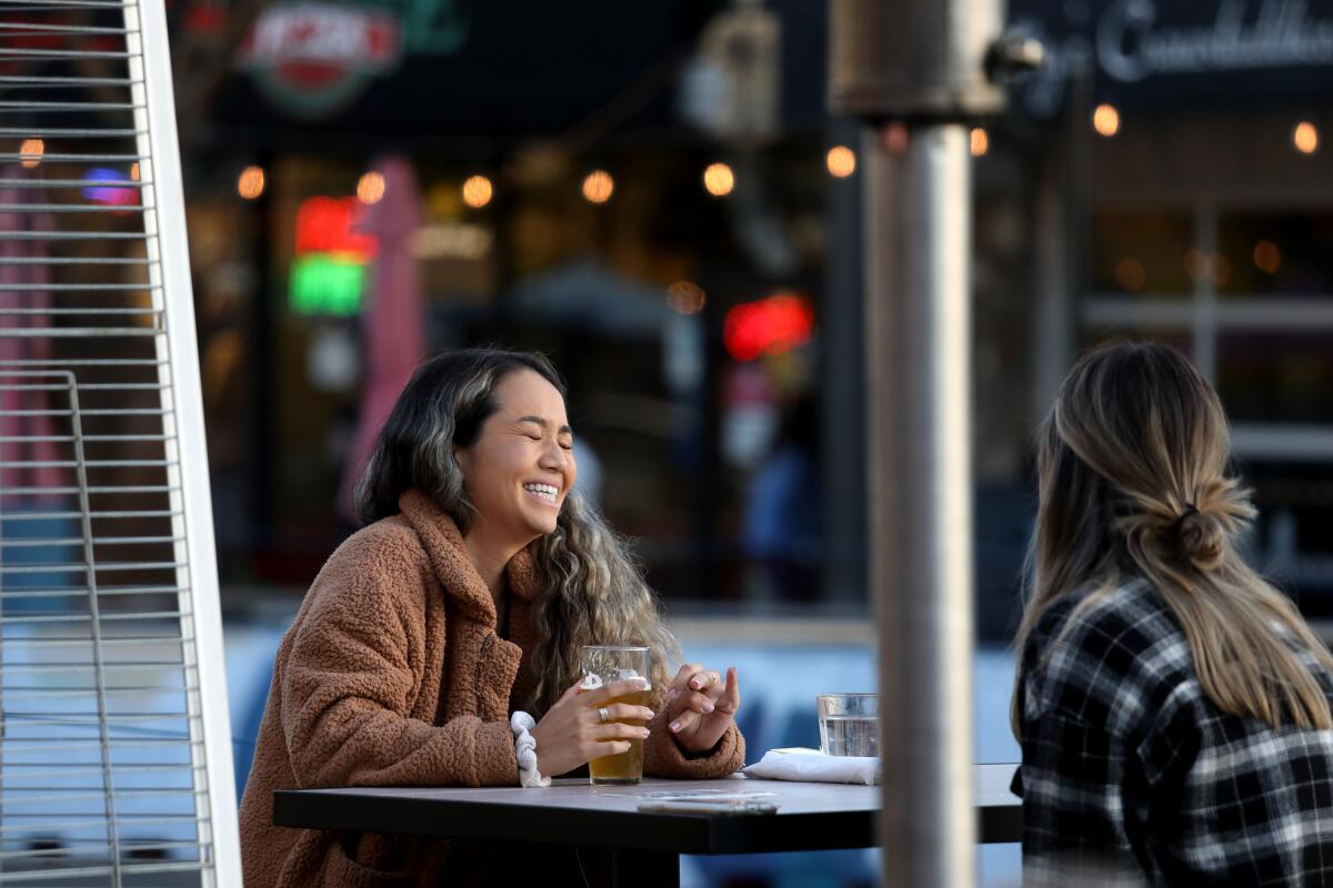 People sit unmasked at an outdoor table in Redondo Beach. 